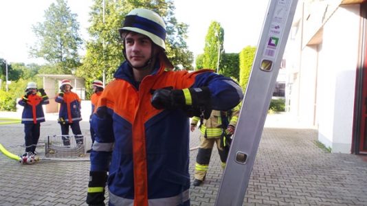 Die Steckleiter ist aufgebaut, Sebastian prüft, ob die Leiter korrekt steht.